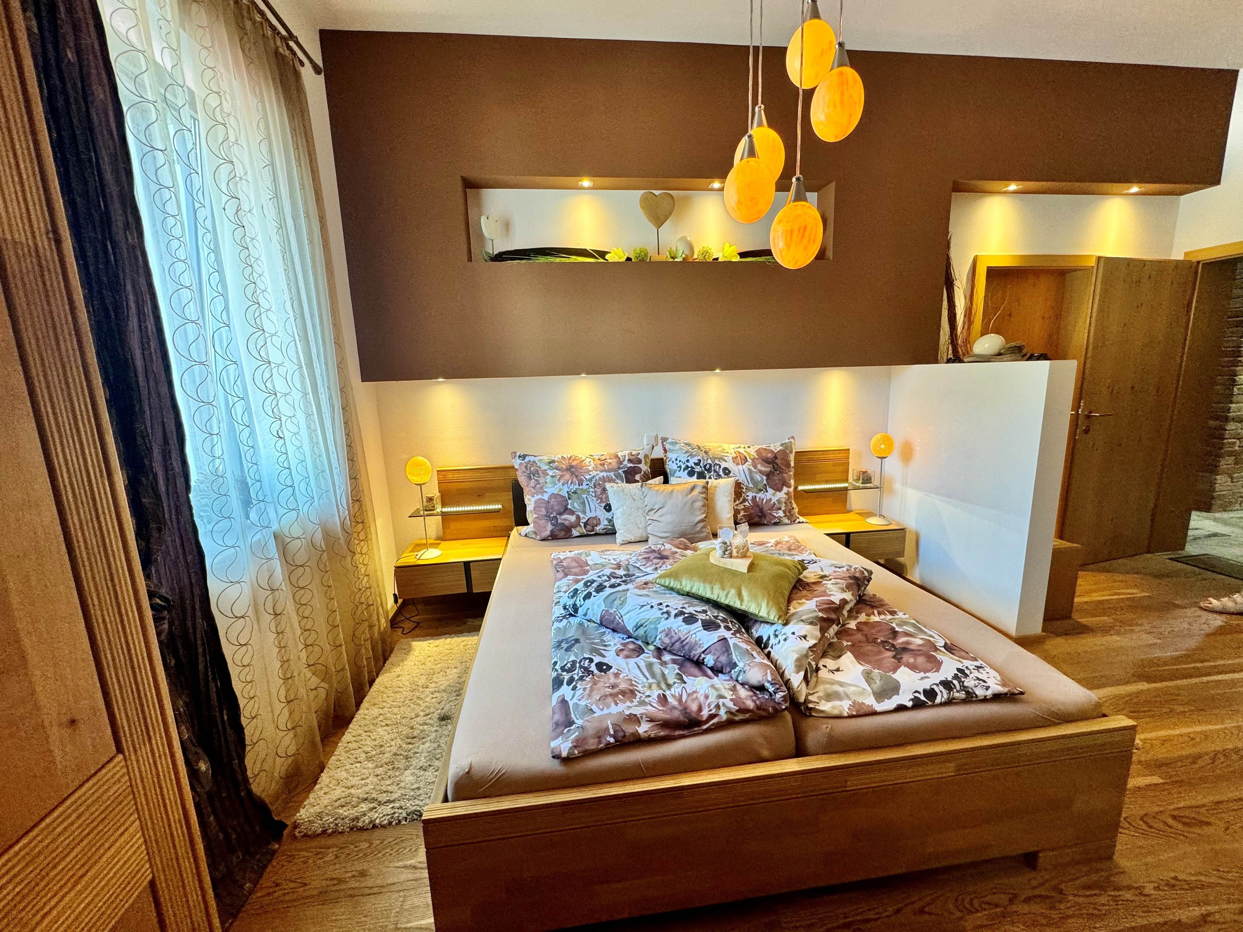 A cozy bedroom with a double bed, decorative pillows, and warm light that fills the room from the ostrich egg lamps.