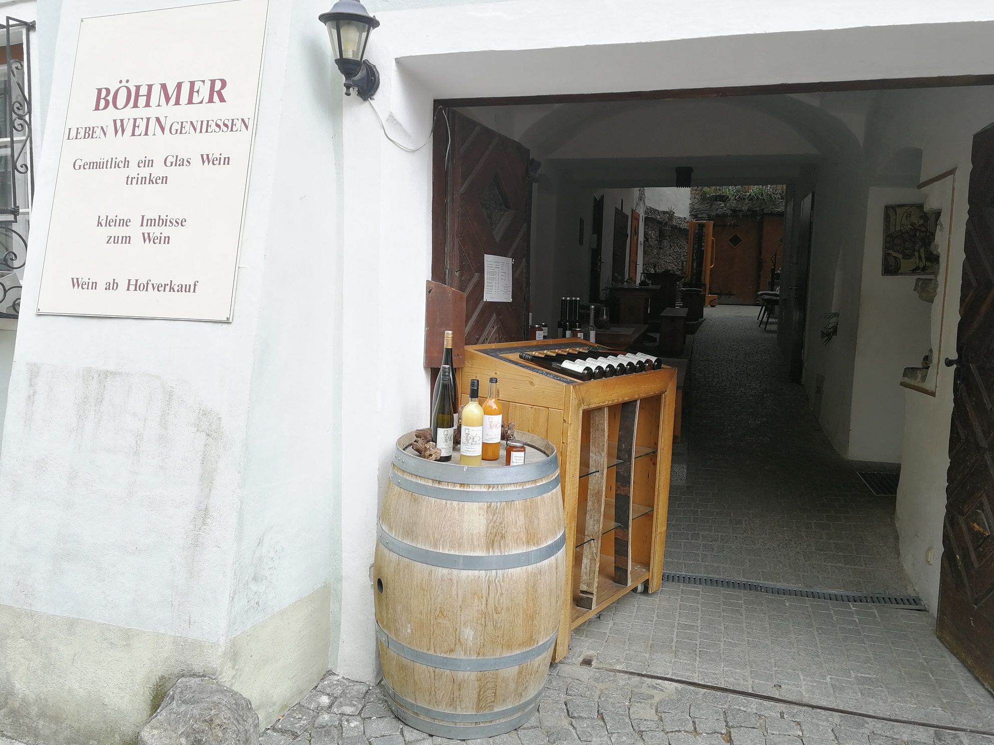 Entrance to a winery with wine barrel and bottles.