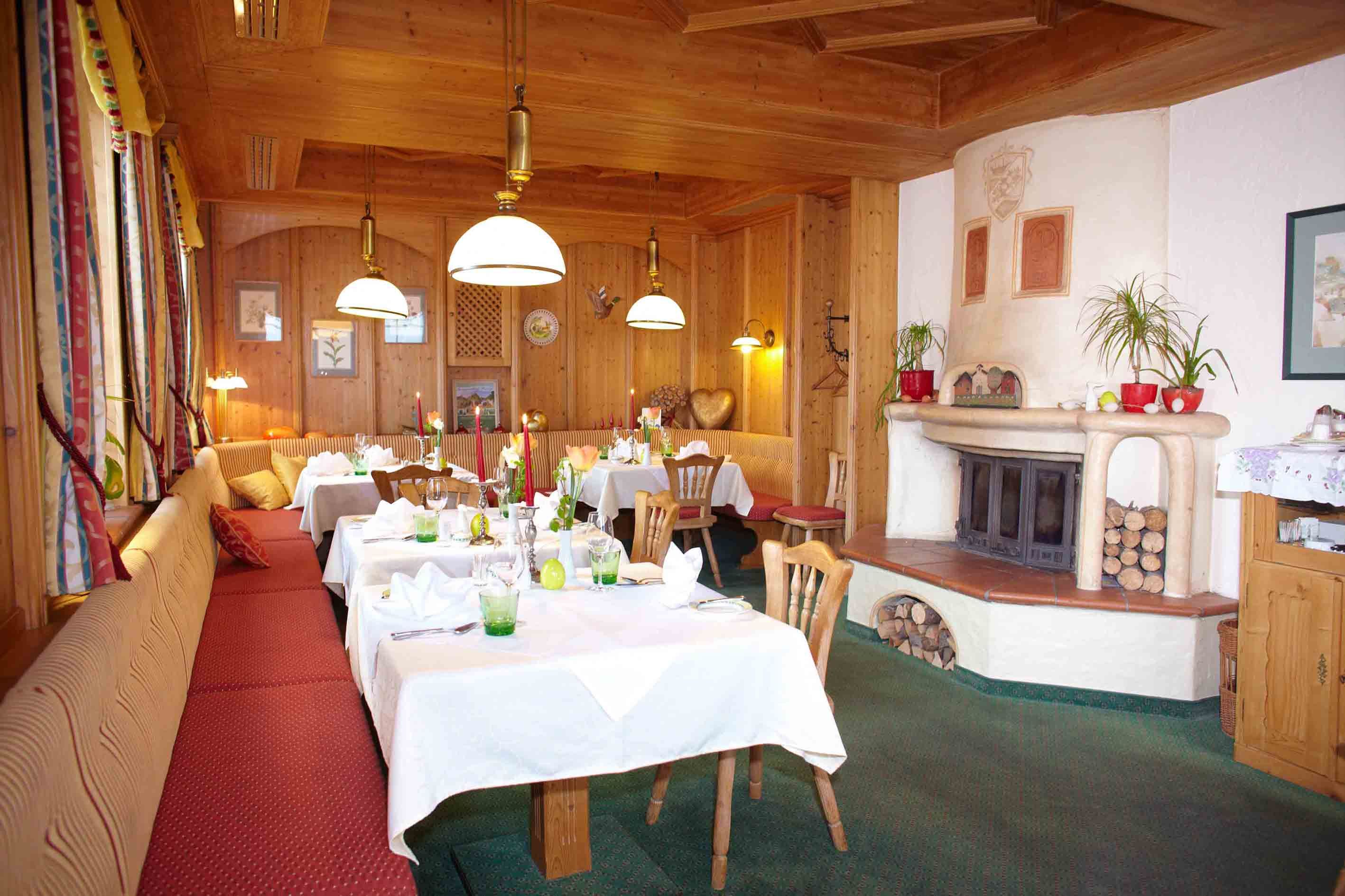 Cozy room with wooden walls, covered tables and fireplace.