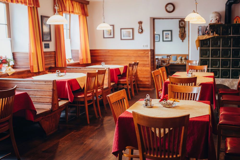 Cozy dining room with wooden furniture, red tablecloths and yellow curtains, in the style of the 1940s.