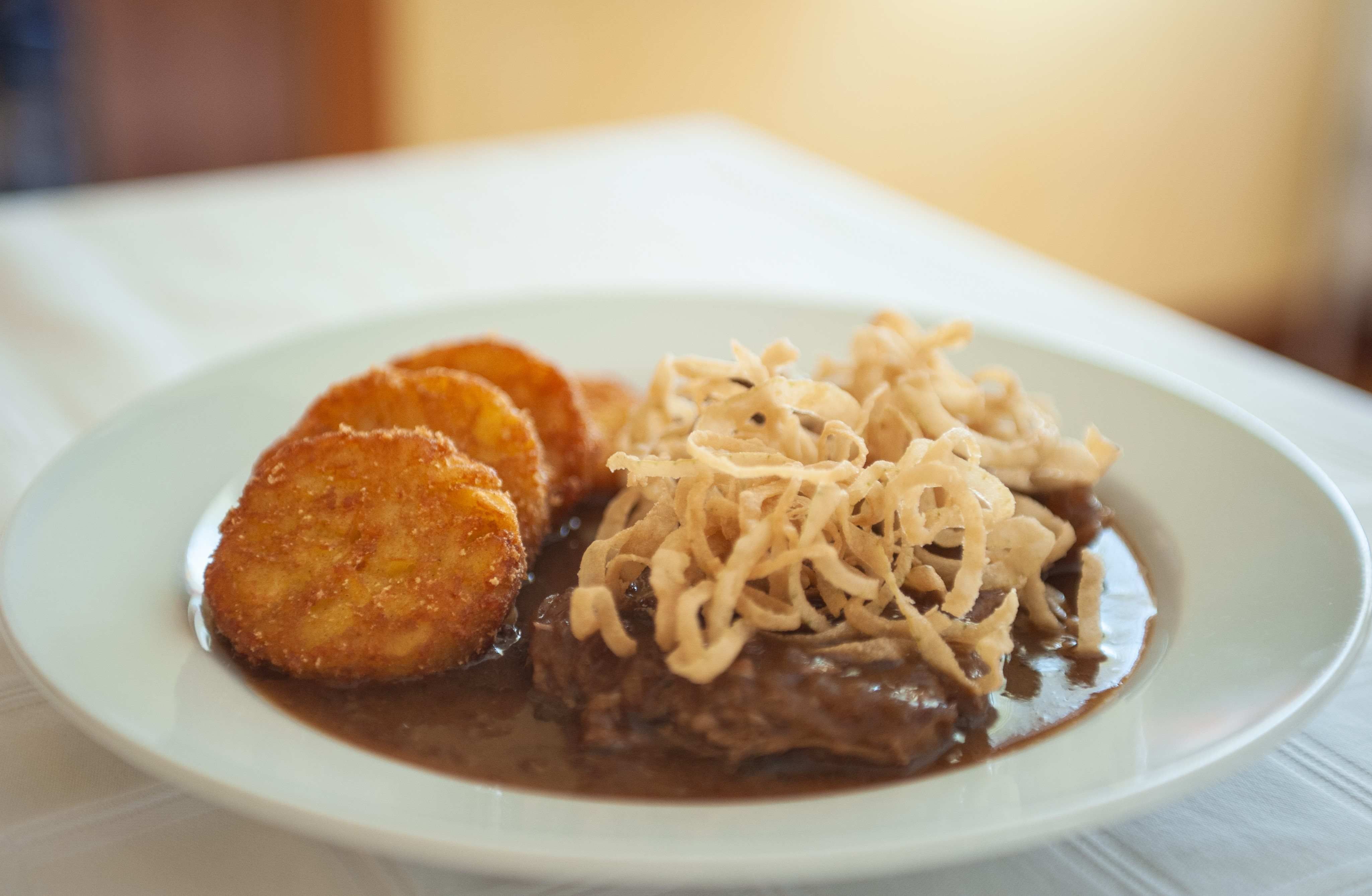 A plate with hash browns, gravy and fried onions.