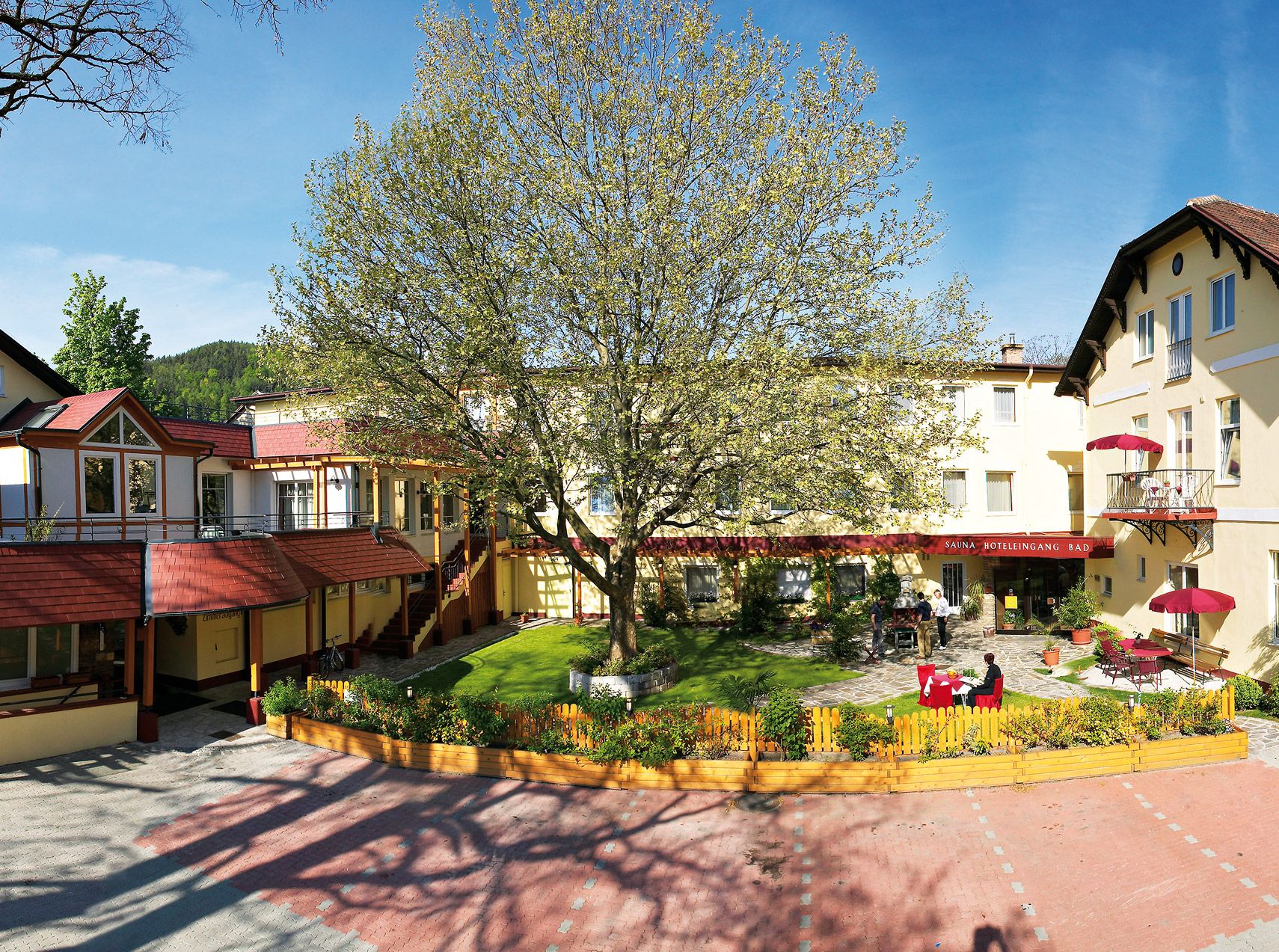 Exterior view of the Hotel Payerbacherhof with large tree in the inner courtyard.