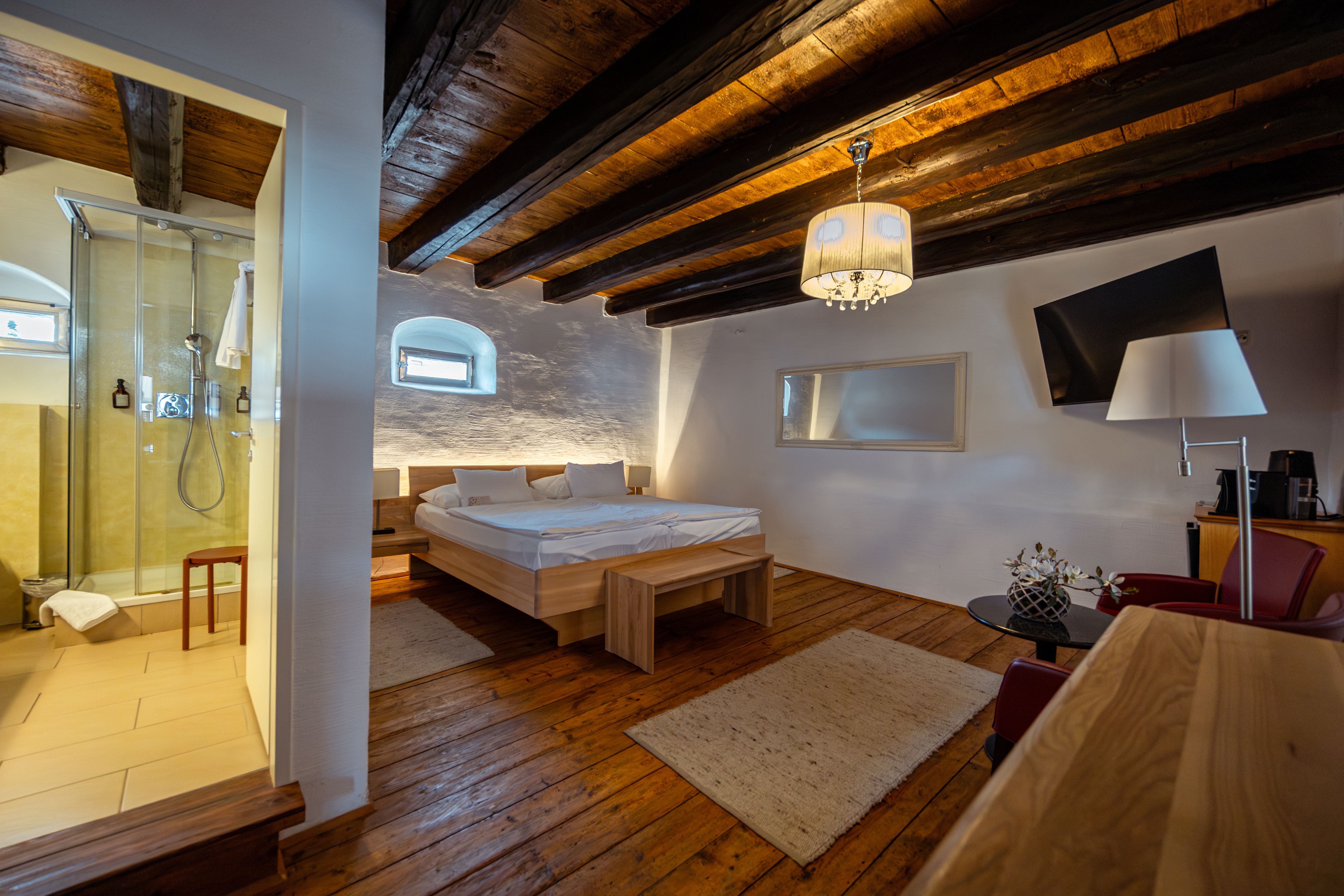 An inner courtyard with cobblestones, tables and chairs, surrounded by buildings with arcades and a modern balcony.