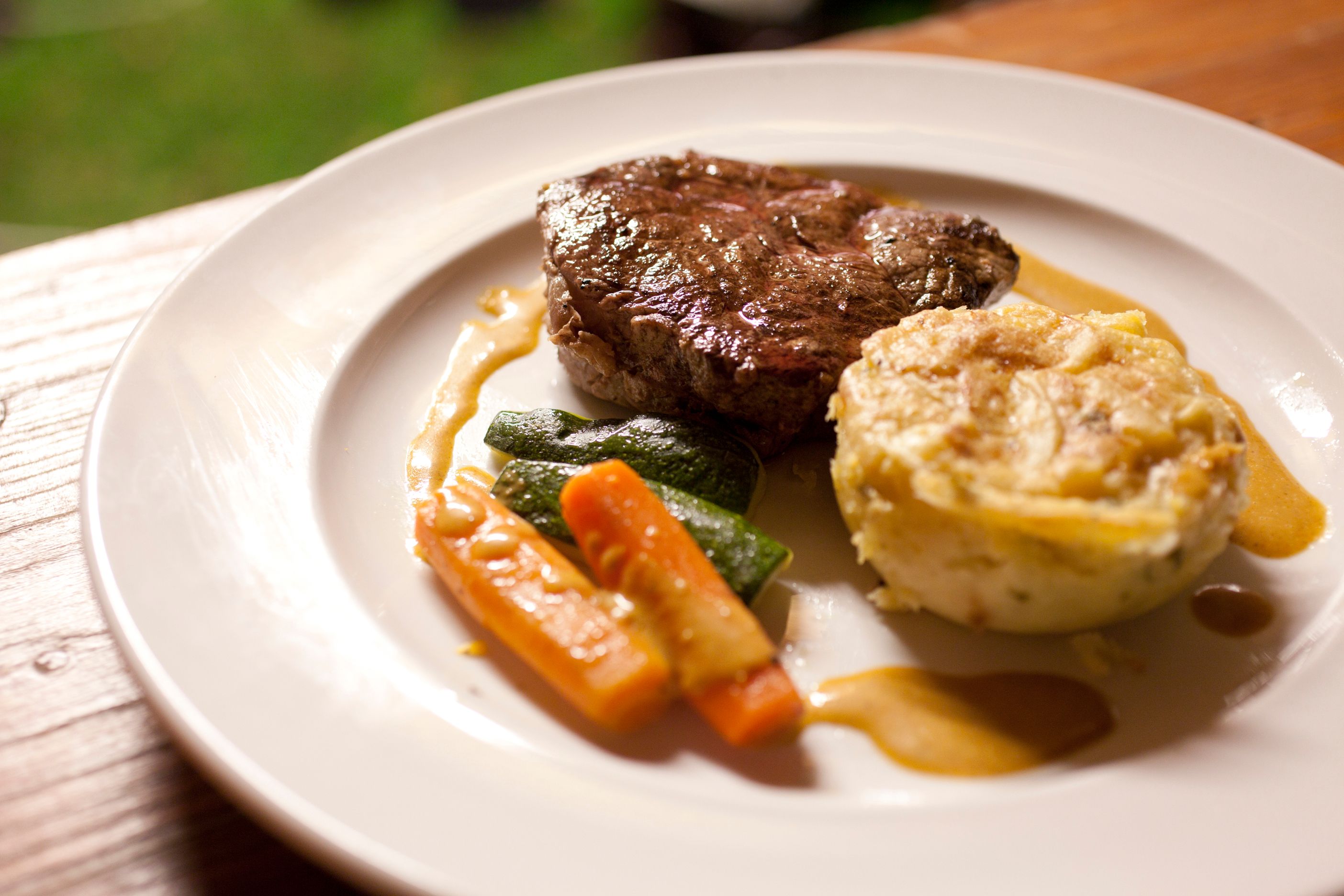 A plate with a piece of meat, vegetables and a potato side dish.