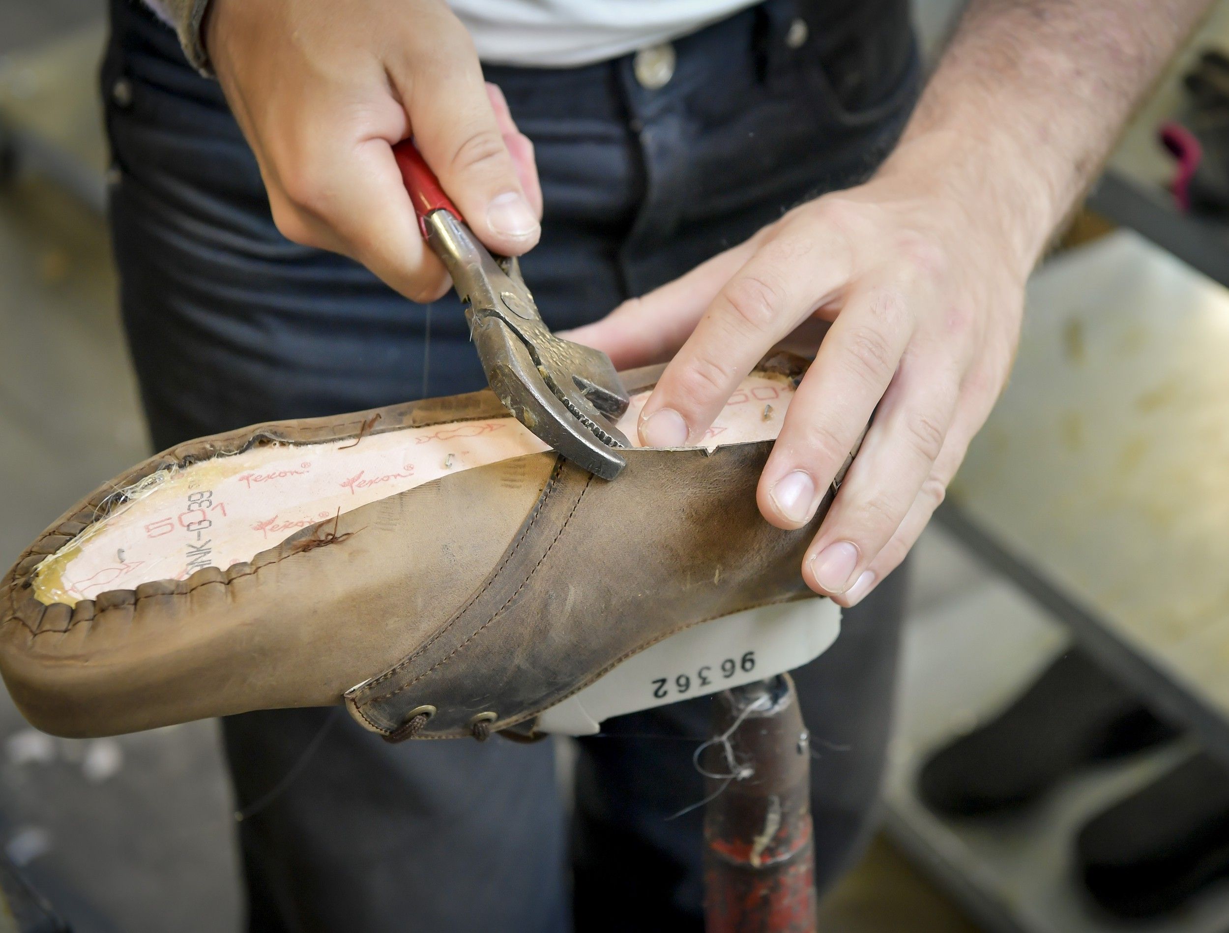 Person works on shoe with pliers on a last.