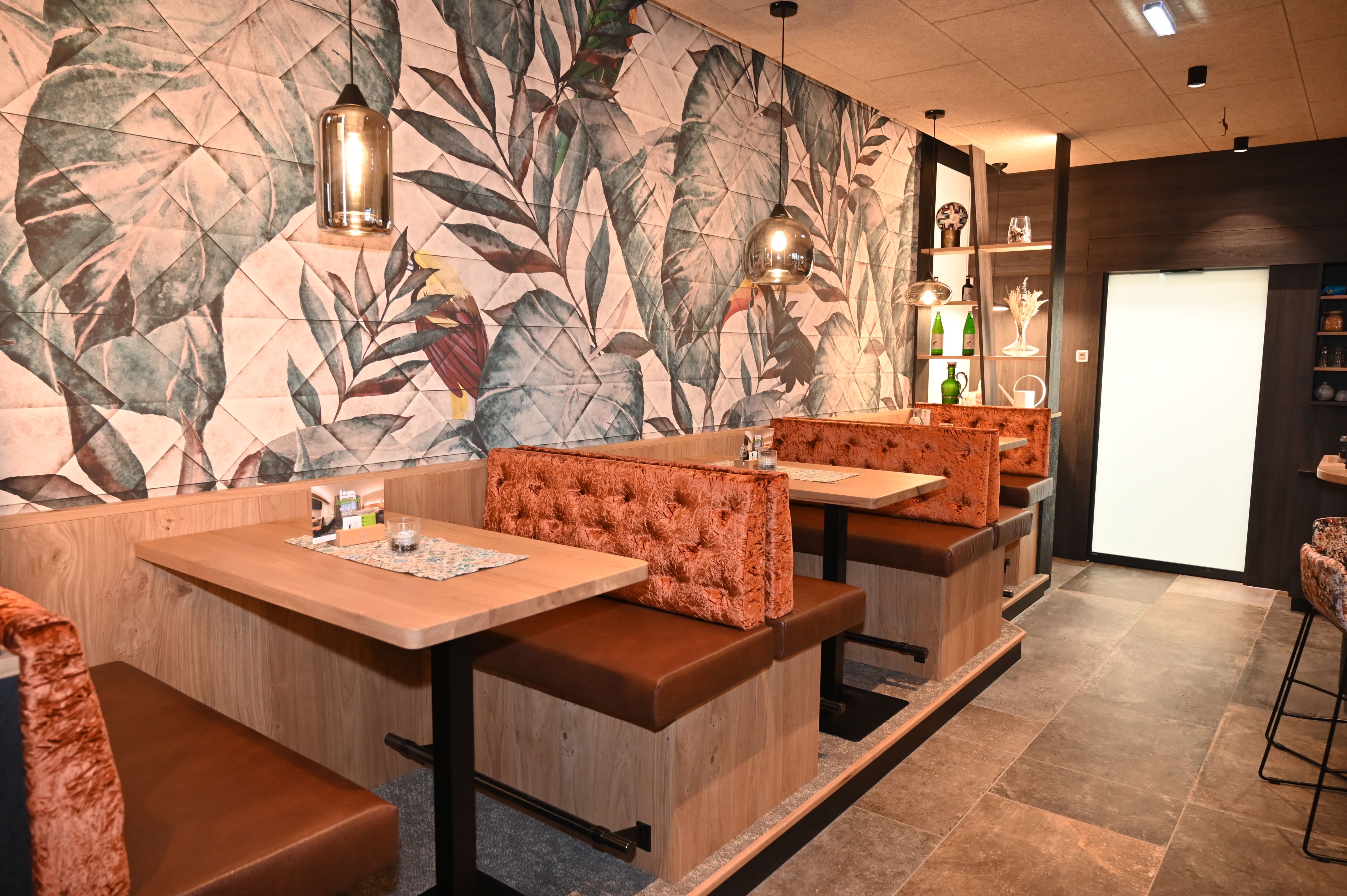 Interior view of a stylish bar with upholstered benches and tropical wall pattern.
