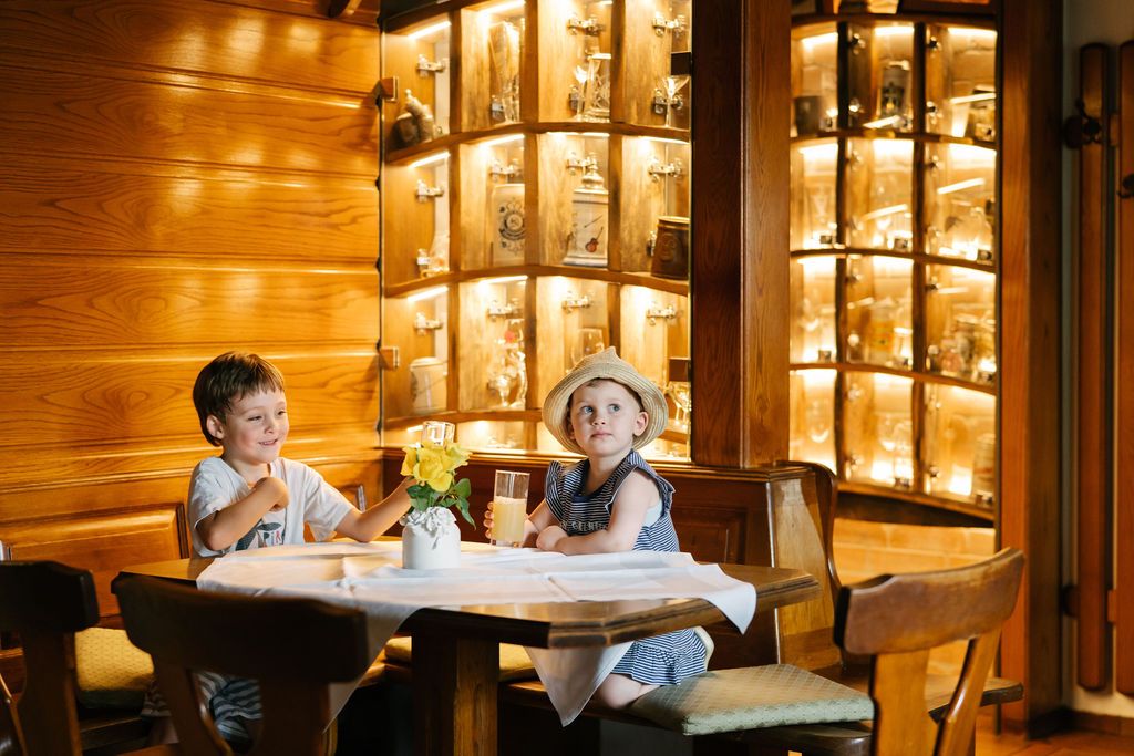 Two children sit at a table in a wood-paneled restaurant.