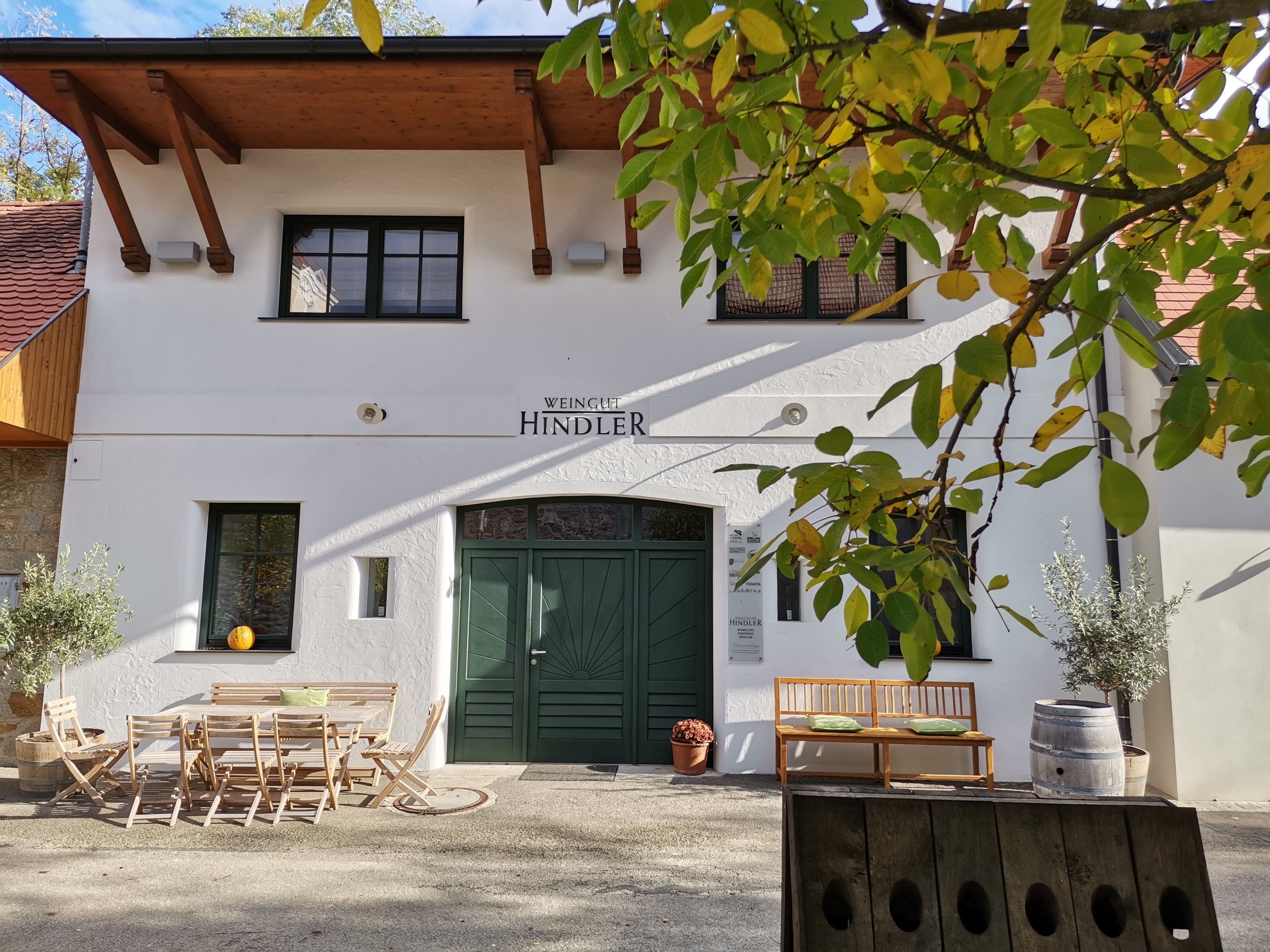 Entrance to a winery with wooden furniture and plants.