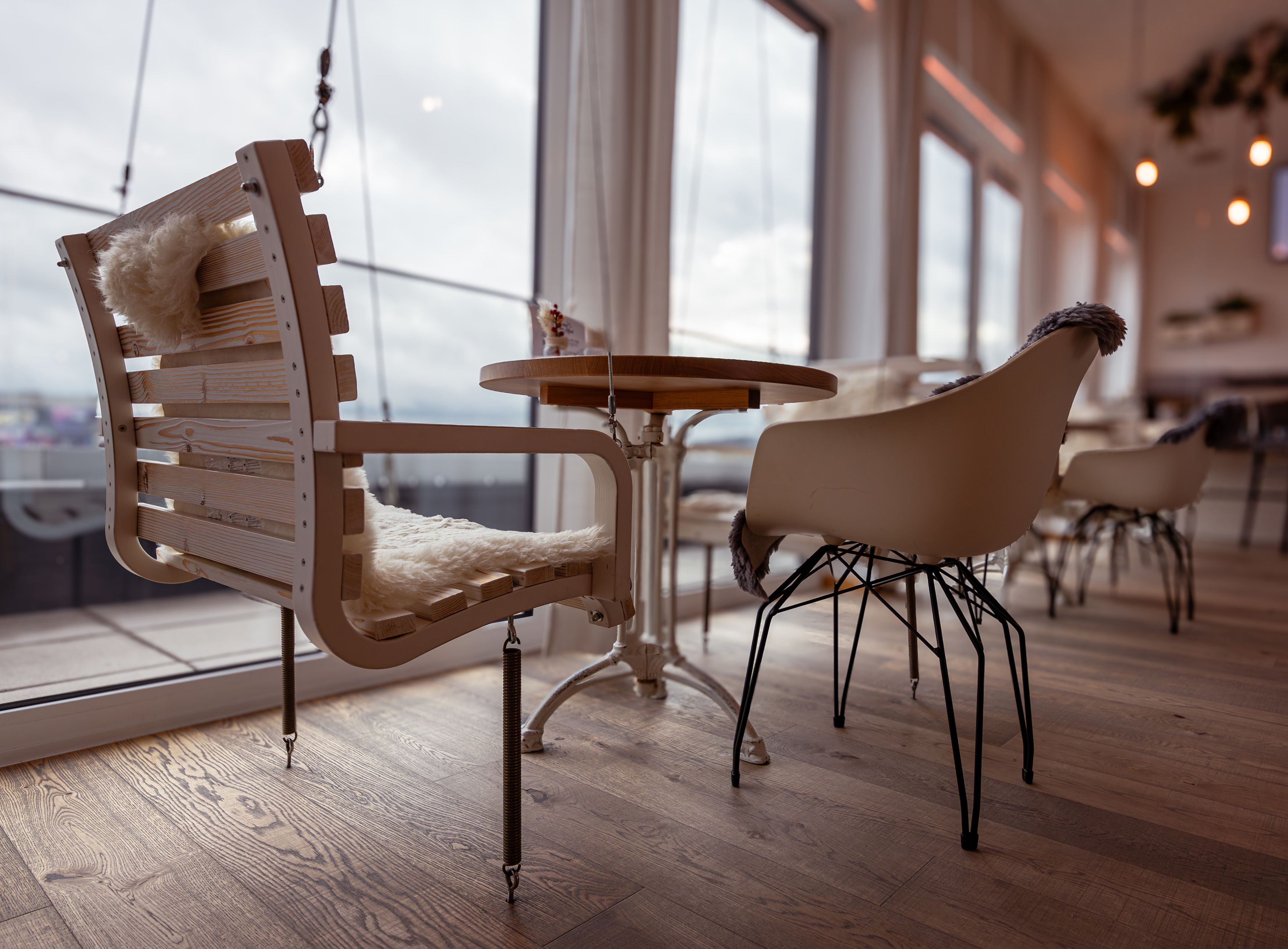 Interior view of a café with modern chairs and wooden table, large windows in the background.
