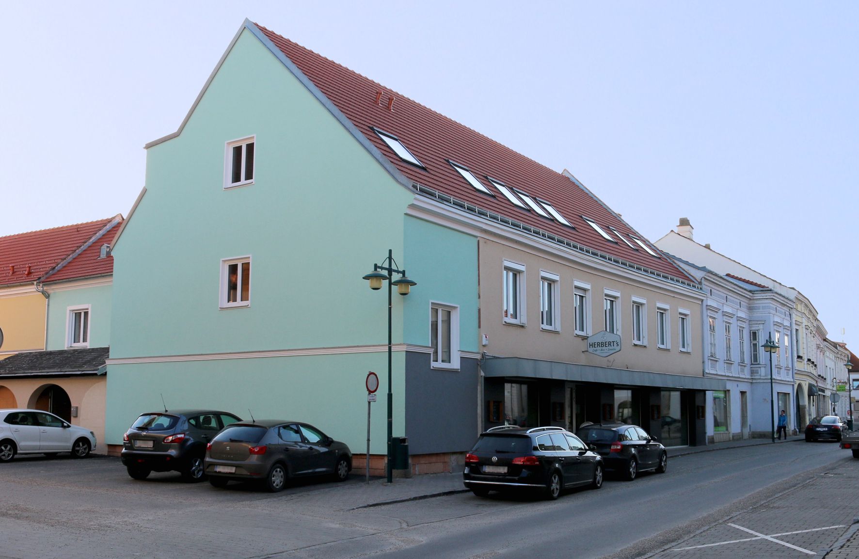 Street scene in Traismauer with multi-storey building and parked cars.