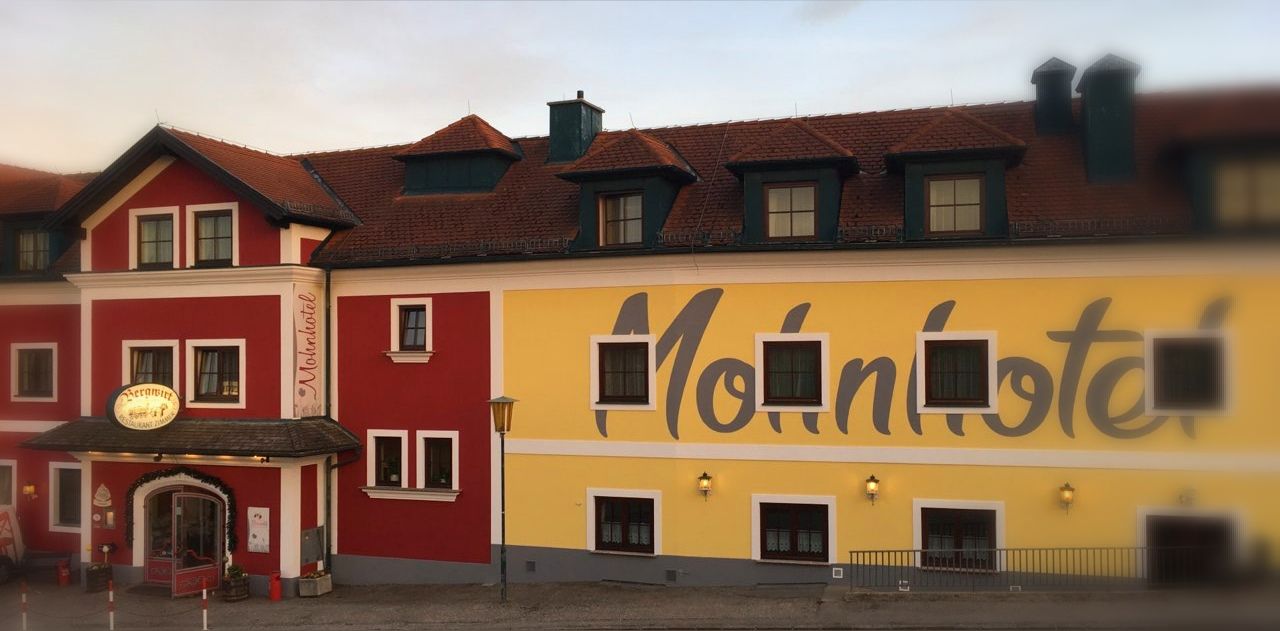 Facade of the Bergwirt Schrammel & Mohnhotel with red and yellow paint.