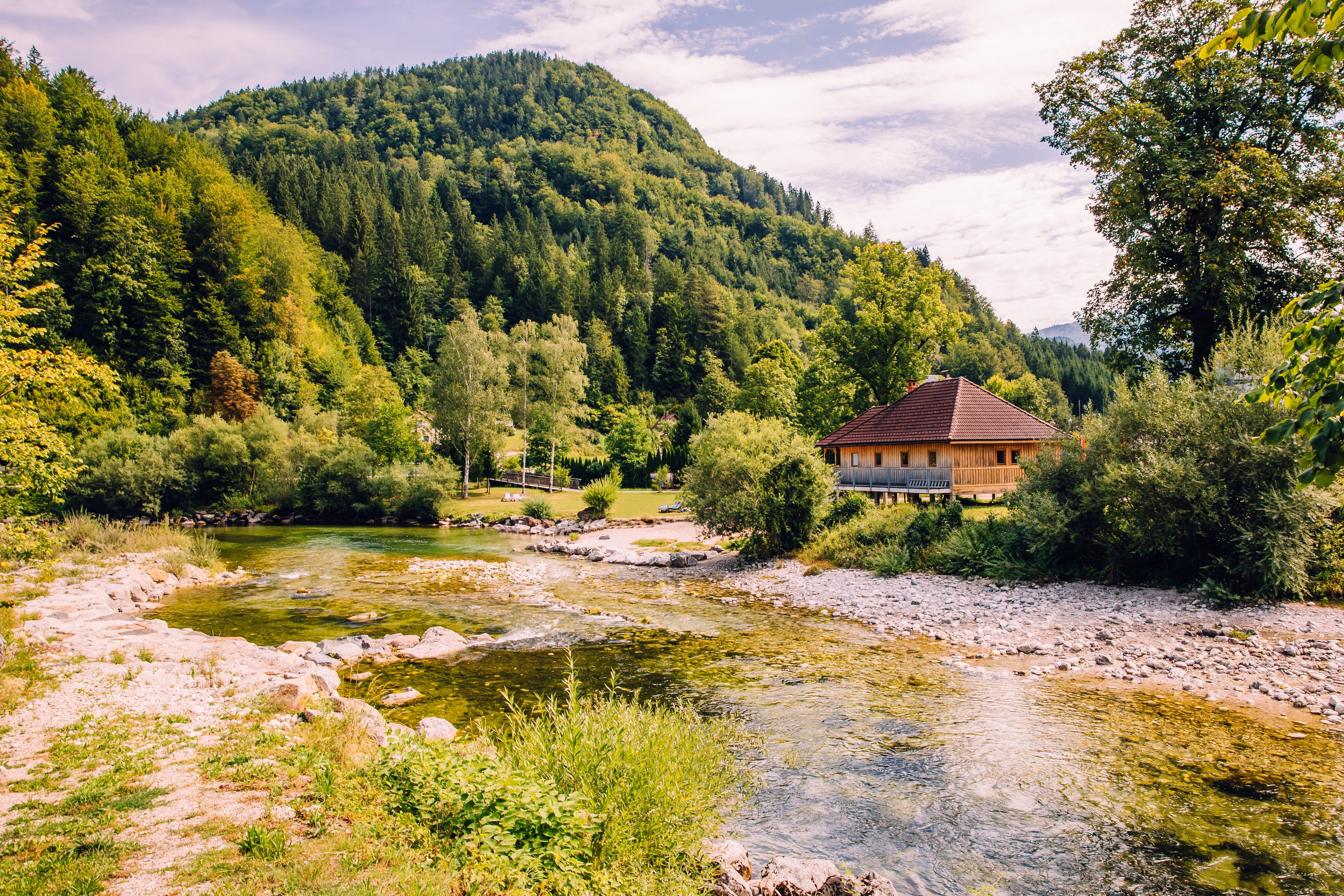 Landscape near Göstling: a clear river, a wooden house on the bank, and forested mountains in the background.