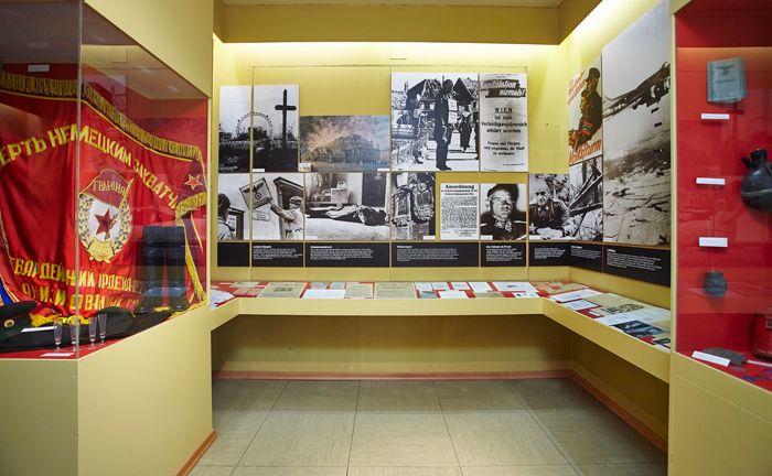 Exhibition room with historical photos, documents and a red flag.