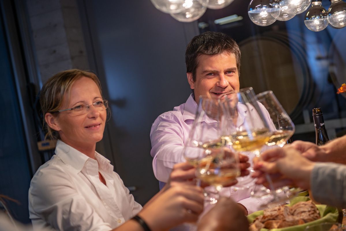 People clink glasses of wine at a table.