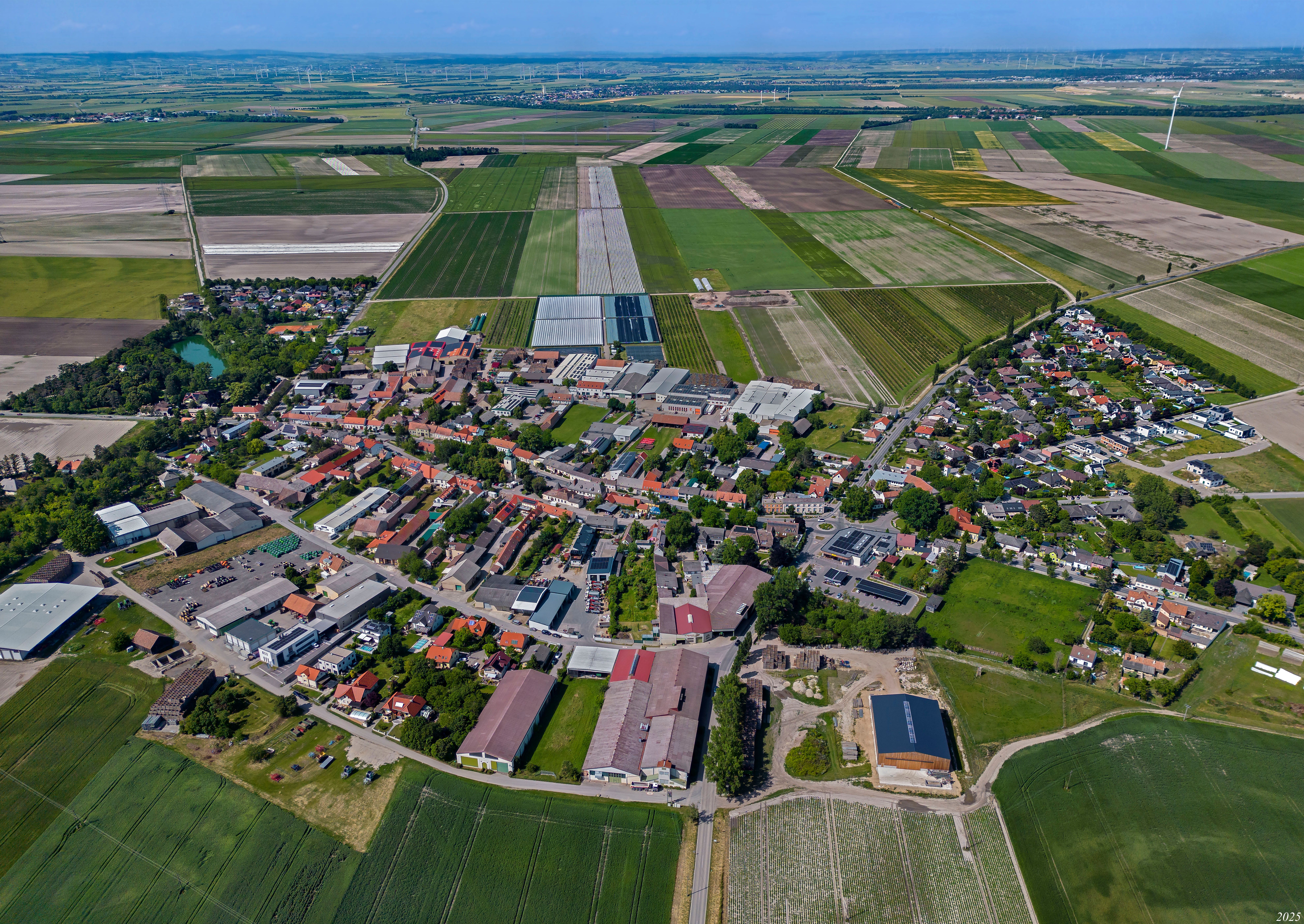 Aerial view of Raasdorf showing the town center, fields, greenhouses, and wind turbines in the surrounding area.