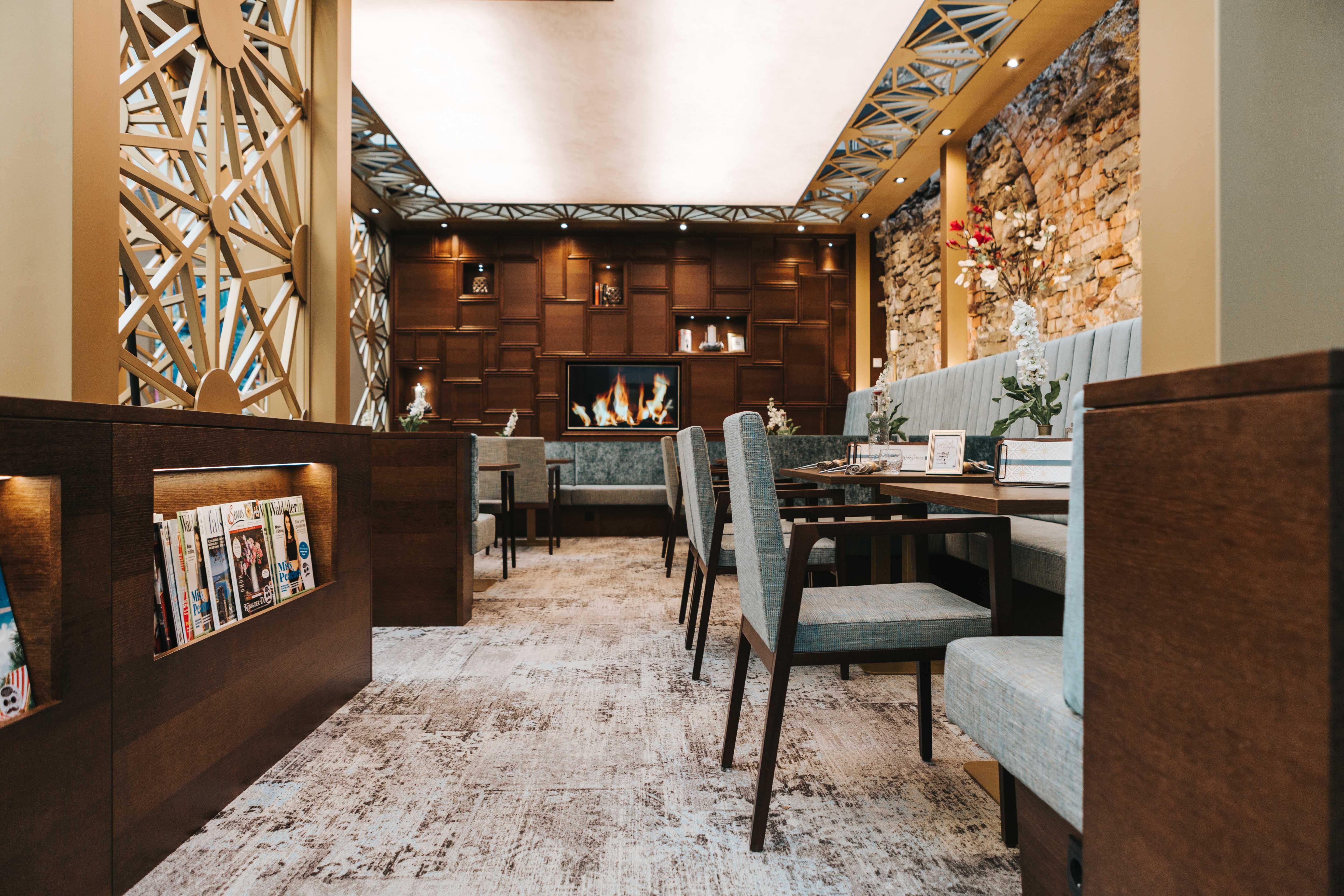Interior view of a stylish café with cozy seating, fireplace and magazine rack.