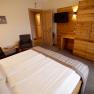 Bedroom with double bed, wooden furniture and TV on the wall.