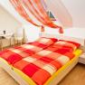 Bright bedroom with red comforter cover and decorative curtains.