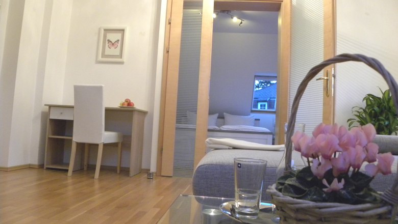 Interior with desk, chair, flowers in a basket and view into the bedroom.