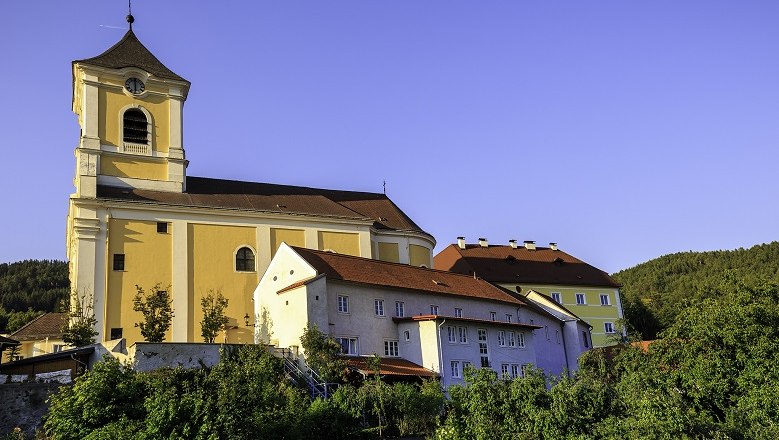 Church with adjoining monastery on a hill under a clear sky.