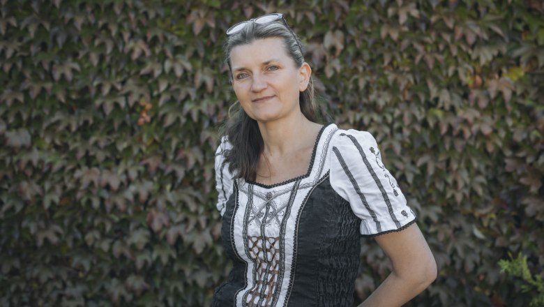 Woman in traditional dress in front of a wall overgrown with ivy.
