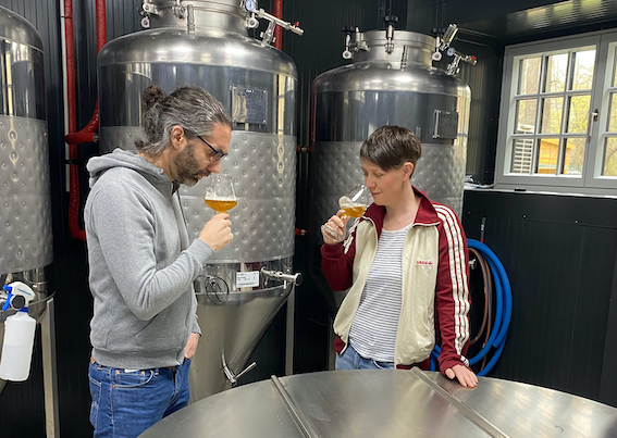 Interior view of a modern café with wooden beams, bar counter and tables.