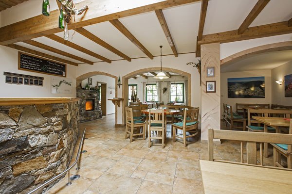 Interior view of a cozy dining room with wooden beams, stone bar and wooden furniture.