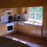 Modern kitchen with wooden cupboards, stove, sink and window.