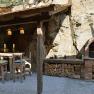 Rustic outdoor area with wooden table, chairs and brick oven.