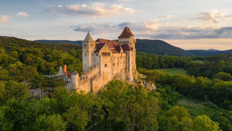 Liechtenstein Castle in the middle of green forests at sunset.