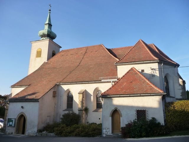 Historic church with red tiled roof and small tower with green roof.