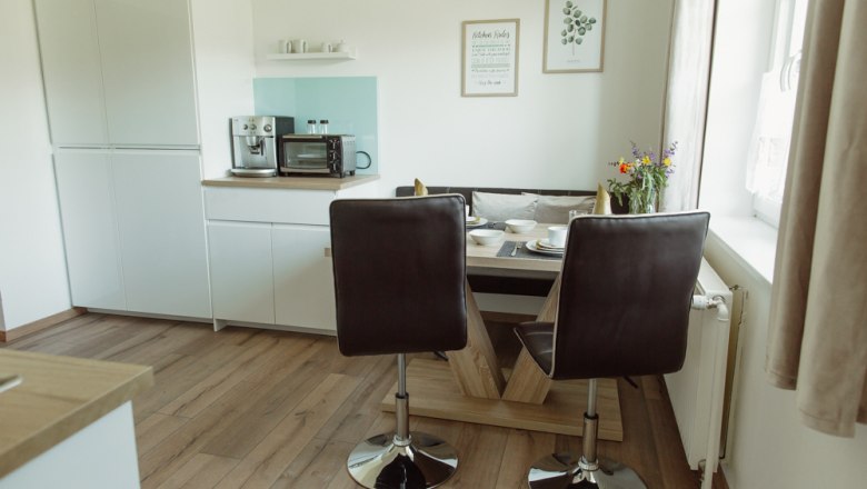 Modern kitchen with dining table, chairs and appliances.