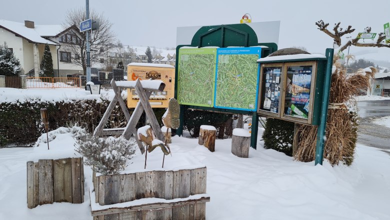 Winter hiking starting point with information boards and snow in front of the Krumbacherhof.