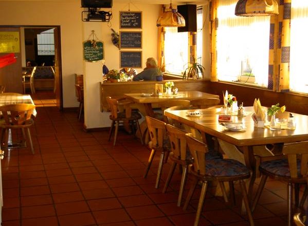 Cozy dining room with wooden tables and chairs, decorated with flowers and napkins.