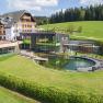 Hotel Schwarz Alm Zwettl with natural pond and sun loungers, surrounded by green countryside.