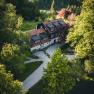 Aerial view of a traditional house in the countryside, surrounded by trees and a well-tended garden.