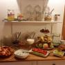 A breakfast buffet with fruit, bread, spreads and muesli in a cozy room.