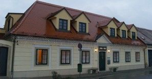 Two-storey building with yellow façade and red roof.