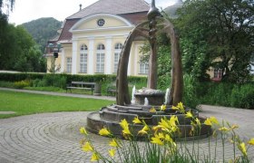 Fountain in front of a historic building with yellow flowers in the foreground.