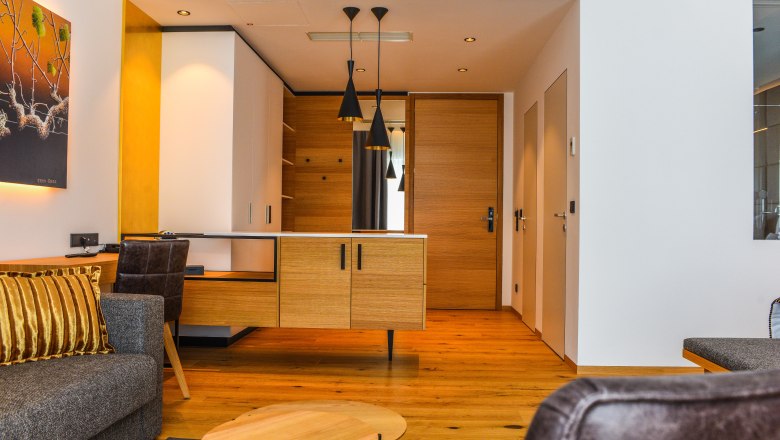 Interior view of a modern hotel suite with wooden floor, gray sofa and wooden desk.