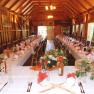 Interior view of a festively decorated hall with long tables and wooden ceiling.