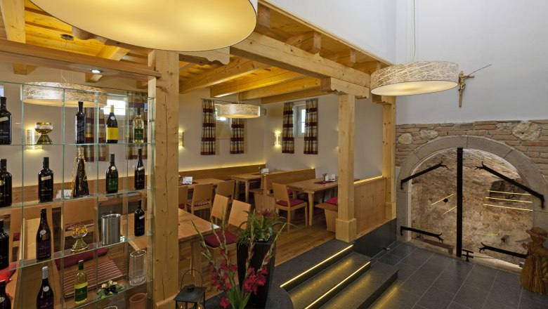 Interior view of a wine tavern with wooden furniture, wine rack and decorative lamps.