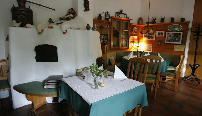 Cozy inn with rustic furnishings, wooden furniture and tiled stove.