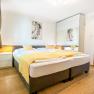 Modern bedroom with double bed, yellow comforter and large closet with mirrors.