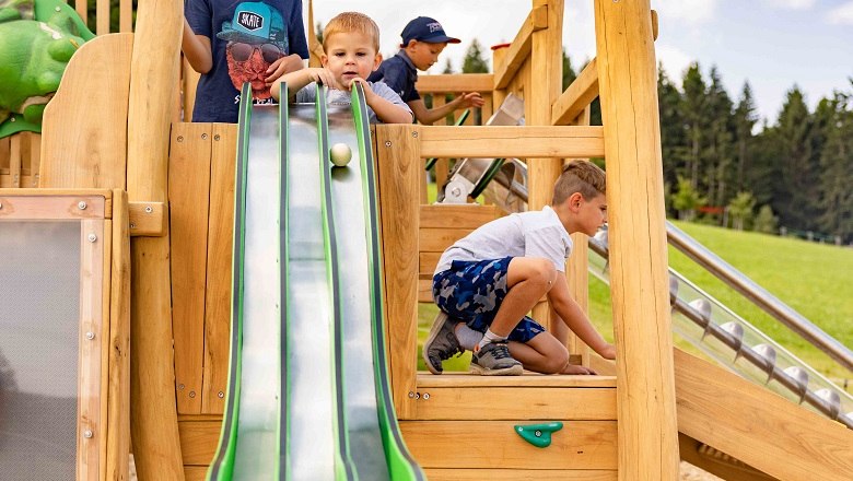 Children playing on a wooden playground with a marble run.