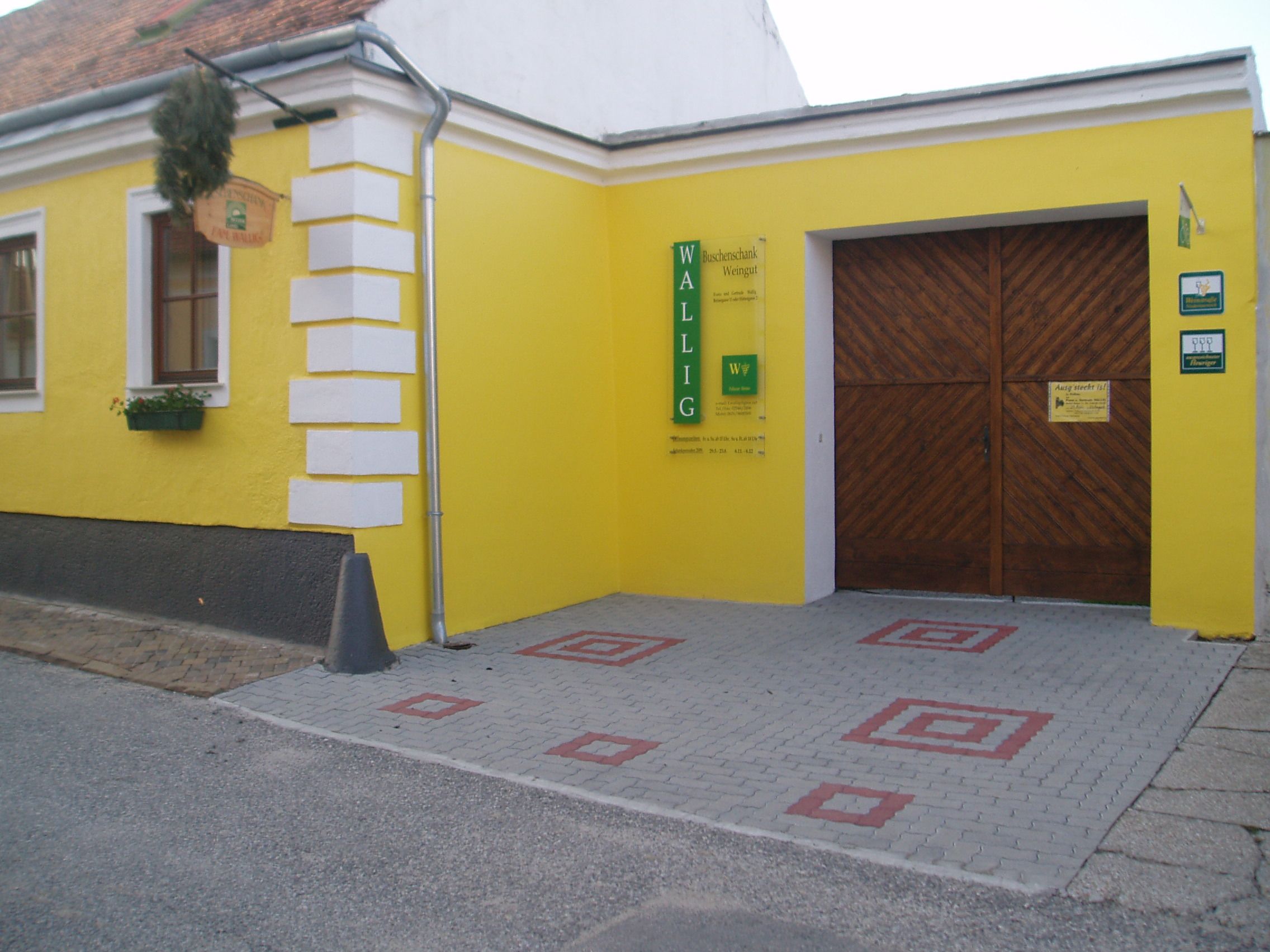 Yellow building with wooden gate and sign 'Wallig'.