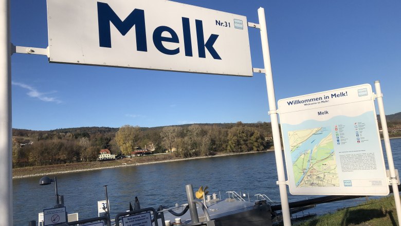 Landing stage in Melk on the Danube with signs and river in the background.