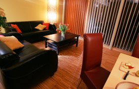 Cozy living room with leather sofas, coffee table, bouquet of flowers and dining table with fruit.