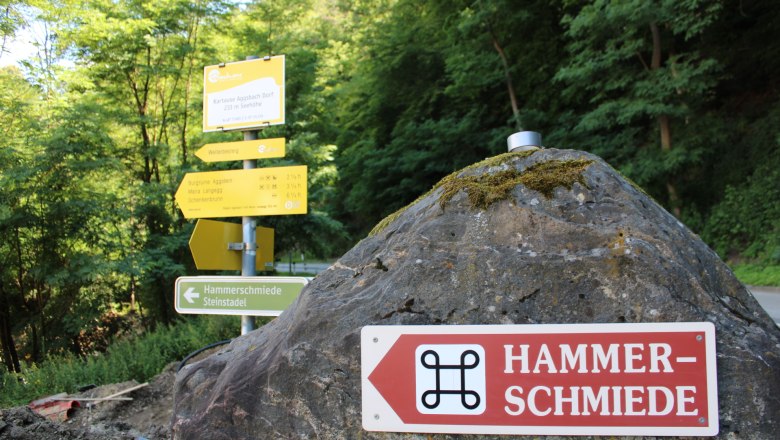 Signpost to the hammer mill in Aggsbach, surrounded by trees.