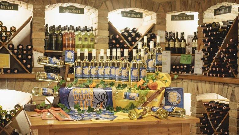 Wine racks in a wine cellar with bottles and decoration on a table.